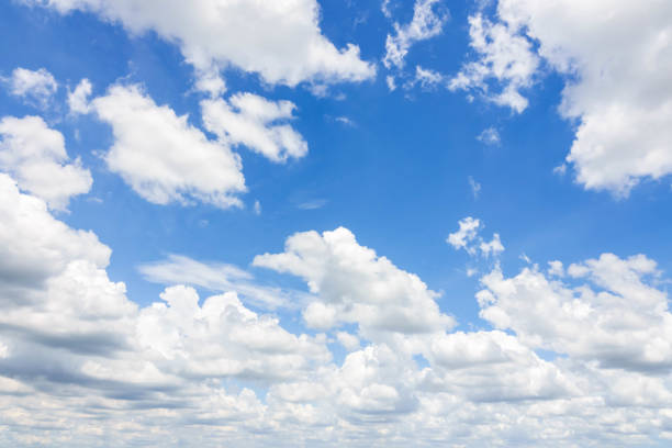 white fluffy light clouds in a bright blue sky stock photo