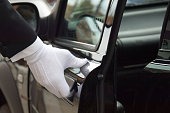 istock White formal gloved uniformed hand opening car door 151520574