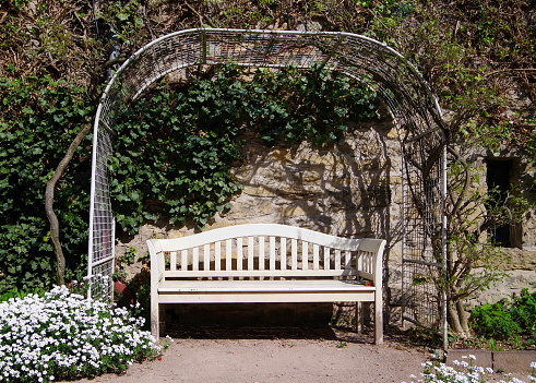 White Garden Bench With Back Under A Rose Arch Stock Photo