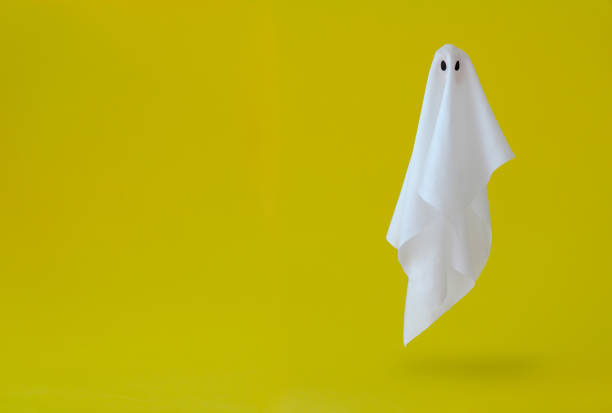 costume da lenzuolo fantasma bianco che vola in aria con sfondo giallo. - fantasma foto e immagini stock