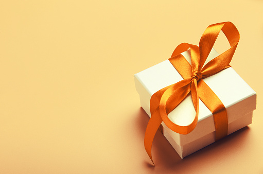 White Gift Box With Orange Bright Ribbon On Yellow