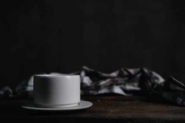 White handmade ceramic coffee cup on dark rustic table, black background. stock photo