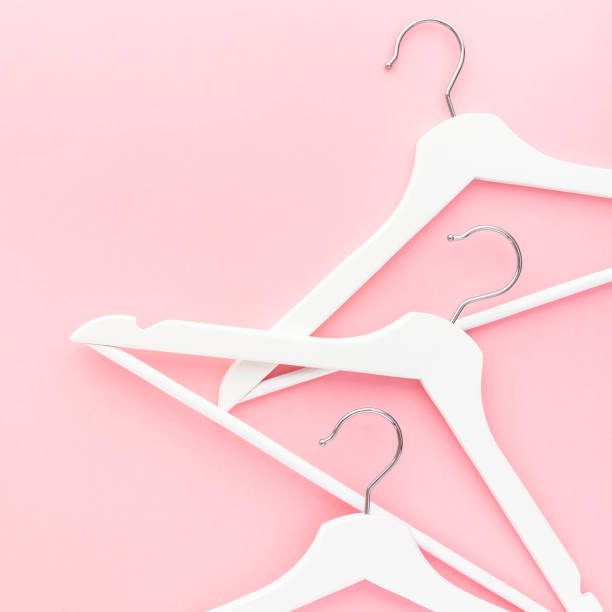 White hangers on pastel pink background stock photo