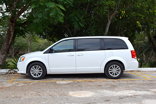Uxmal, Mexico - 30 December, 2018: White MPV vehicle Dodge Grand Caravan parked on the street. This model is popular family car in North America.