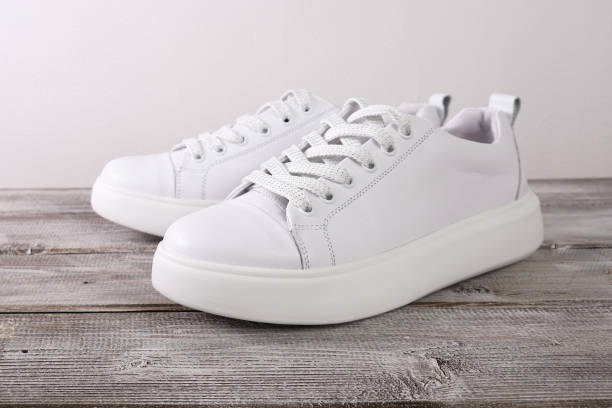White leather casual sneakers on wooden background stock photo