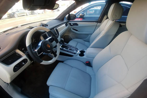 White leather interior of an premium SUV Porsche Macan parked on the street. Package trim car of white oak and wooden heated steering wheel. stock photo