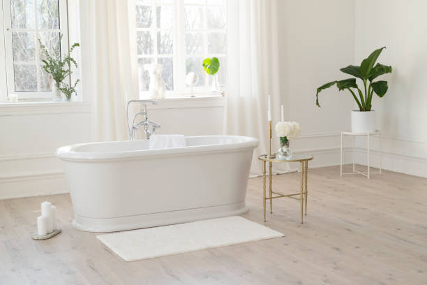 White modern bathroom with silver fittings with large sunny windows, decorations and plants. Interior design concept. Soft selective focus. White modern bathroom with silver fittings with large sunny windows, decorations and plants. Interior design concept. Soft selective focus bath tub stock pictures, royalty-free photos & images