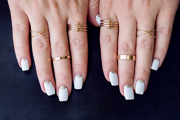White nail art manicure, hands with fashion gold rings White nail art manicure, beauty hands with fashion gold rings. Trendy accessories top view gold ring on finger stock pictures, royalty-free photos & images
