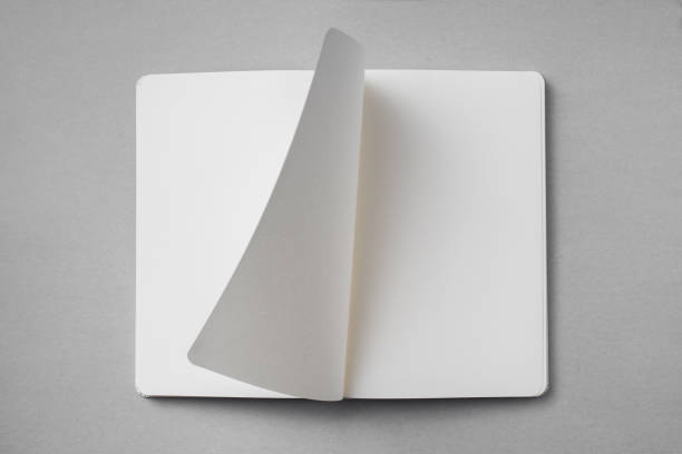 white notebook with turn page on grey background Design concept - top view of white notebook with blank open, turn and flipped page on grey background for mockup. real photo, not 3D render turning stock pictures, royalty-free photos & images
