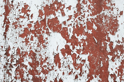 White paint flaking and cracking texture on rusty metal. 
