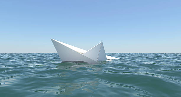 White paper boat is sinking in the sea water stock photo