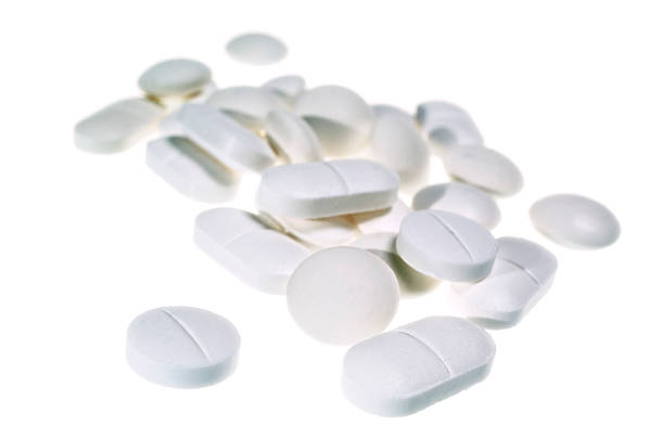 white pile of painkiller pills isolated - pijnstiller stockfoto's en -beelden