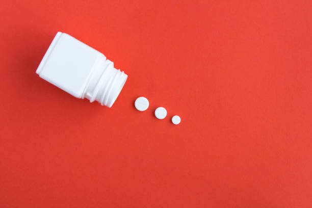 White pills  and bottle on the red background. Top view. Copy space stock photo