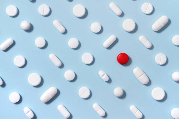 Pengaturan pil putih pada latar belakang biru lembut dengan satu pil merah menonjol dari mereka