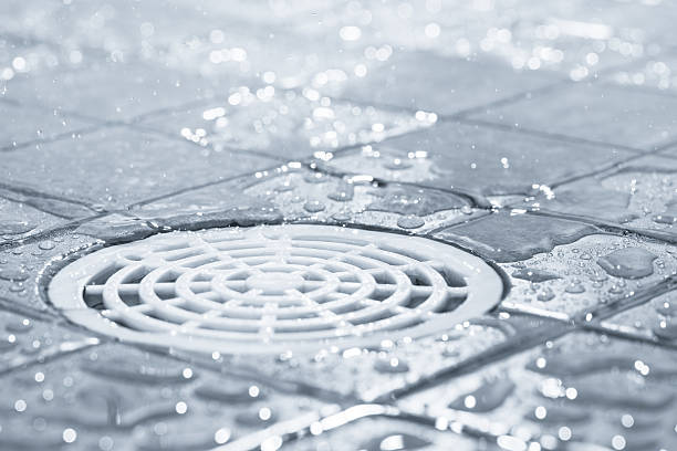 White plastic shower drain with drops of water around it stock photo