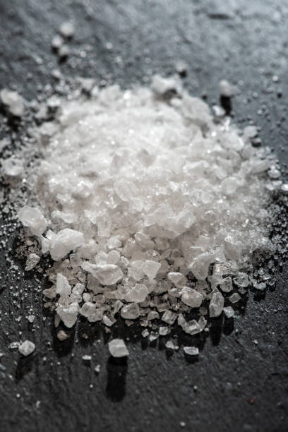 White salt crushed on dark stone background. Close-up Big pieces of...