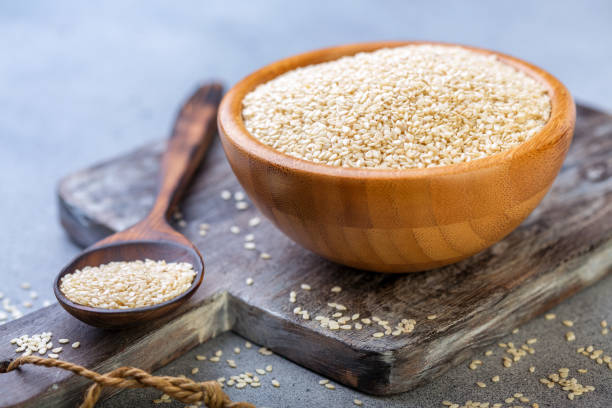 White sesame seeds in a wooden bowl and spoon. stock photo
