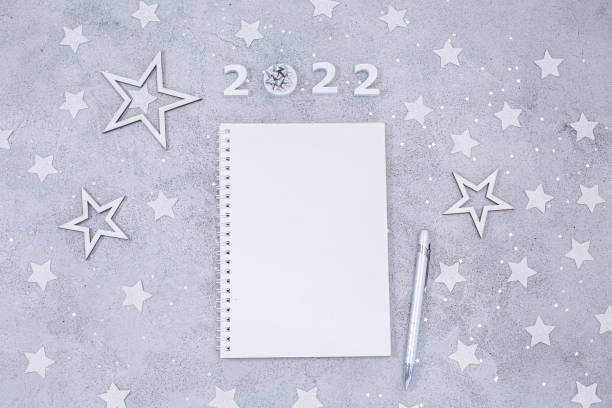 White sheet of notebook with pen on festive gray background. stock photo