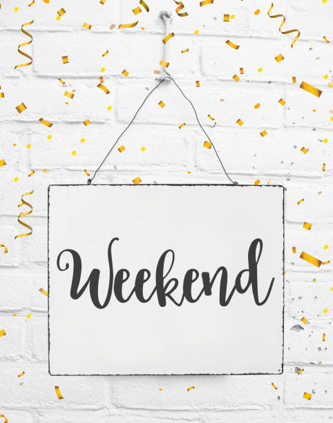 White sign board with text happy weekend with golden confetti on white brick background stock photo