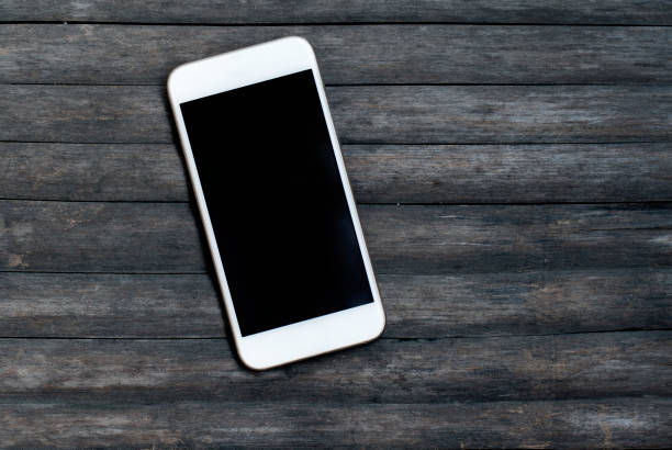 White smartphone on grey wooden background. Personal device mockup stock photo
