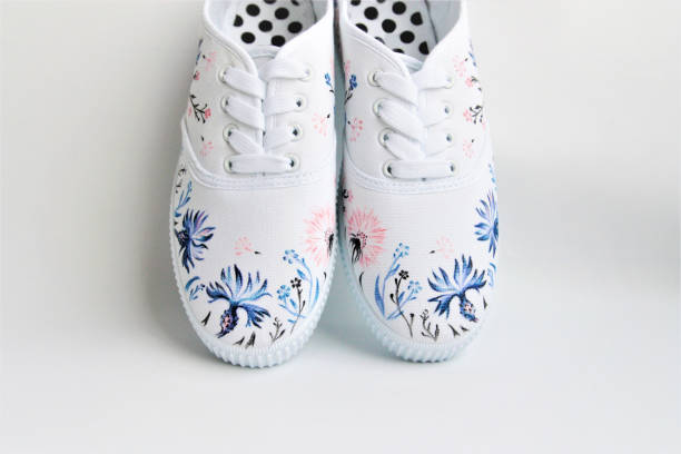 white sneakers with hand-painted wild flowers stock photo
