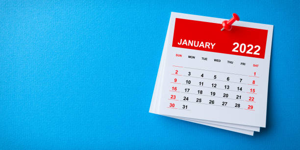White Sticky Note With 2022 January Calendar And Red Push Pin On Blue Background stock photo
