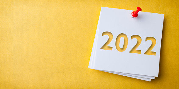 White Sticky Note With Happy New Year 2022 And Red Push Pin On Yellow Background