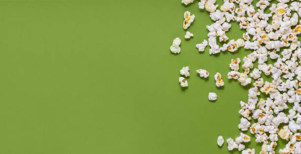 White tasty popcorn on a green background. Popcorn pattern on green background. Top view. Copyspace for your text. stock photo