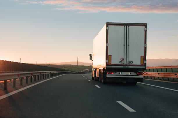White truck driving on empty highway during sunset stock photo