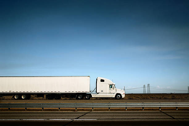 White truck on the road under blue sky White freight truck driving on freeway under blue sky. semi truck side view stock pictures, royalty-free photos & images