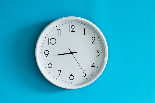 White wall clock on blue background.