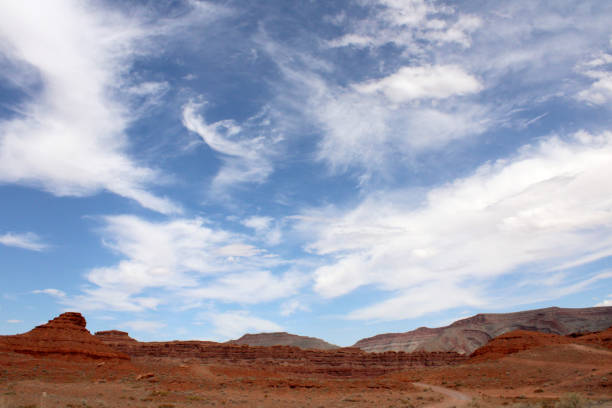 White Wispy Clouds in the Blue Sky Over the Red Utah Desert stock photo
