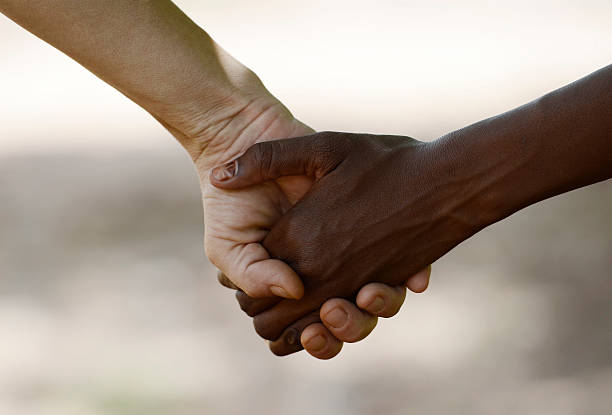 White Woman and African Girl Holding Hands Friendship Symbol stock photo