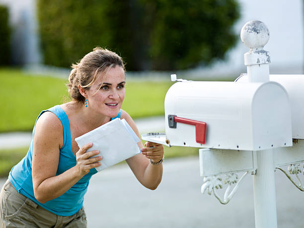 A white woman holding letters looks into an open mailbox caucasian woman picking up the mail (this picture has been taken with a Hasselblad H3D II 31 megapixels camera) direct mail stock pictures, royalty-free photos & images