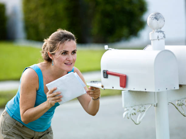 A white woman holding letters looks into an open mailbox caucasian woman picking up the mail (this picture has been taken with a Hasselblad H3D II 31 megapixels camera) direct mail stock pictures, royalty-free photos & images