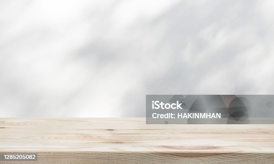 istock White wood table top with shadow of tree leaf on wall background 1285205082