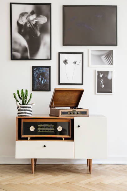 White wooden dresser with vintage radio and old gramophone. Gallery of prints on the wall. Real photo concept White wooden dresser with vintage radio and old gramophone. Gallery of prints on the wall. Real photo concept turntable stock pictures, royalty-free photos & images