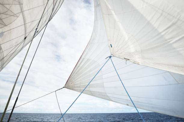 White yacht sails against clear blue sky with lots of clouds. Sailing in an open Mediterranean sea. Idyllic cloudscape. Summer vacations, leisure activity, sport and recreation, private wessel stock photo