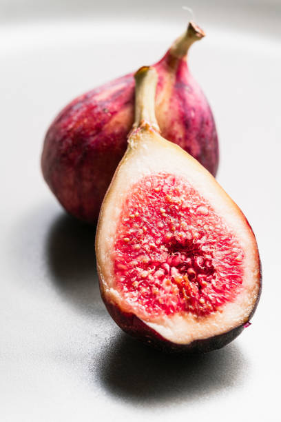 A whole and a cut in half figs on white background. stock photo
