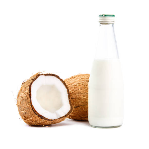 Whole and cut in half coconuts with coconut milk Whole and cut in half coconuts with bottle of coconut milk isolated on white background coconut milk stock pictures, royalty-free photos & images
