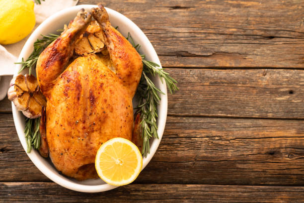 Whole roasted chicken with lemon and rosemary on a black plate. Rustic style. Christmas concept. Christmas turkey. stock photo