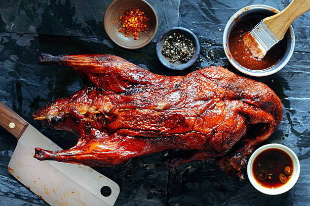 Whole roasted duck Whole roasted duck in marinade on stone background duck meat stock pictures, royalty-free photos & images