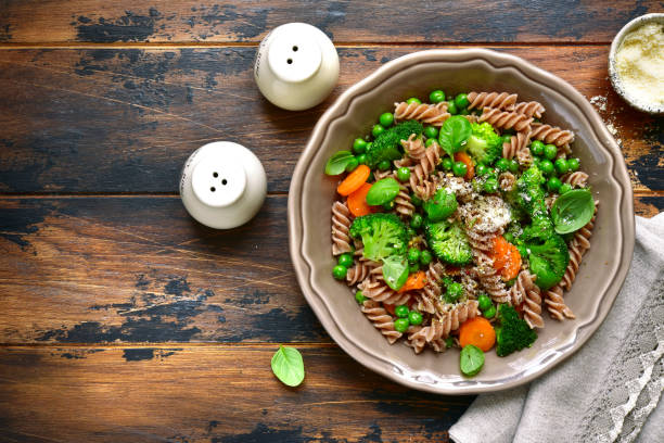 Whole wheat pasta primavera Whole wheat pasta primavera in a rustic bowl on an old wooden background.Top view with copy space. wholegrain stock pictures, royalty-free photos & images