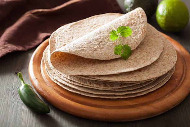 whole wheat tortillas on wooden board and vegetables stock photo