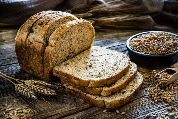Wholegrain sliced bread Wholegrain sliced bread shot on rustic wooden table. A bowl filled with wholegrain spelt is at the right beside the sliced bread. XXXL 42Mp studio photo taken with SONY A7rII and Zeiss Batis 40mm F2.0 CF wholegrain stock pictures, royalty-free photos & images