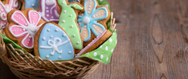 Wicker basket with homemade Easter gingerbread cookies on wooden background. Wicker basket with homemade Easter gingerbread cookies shaped of Easter egg, bunny and flowers decorated with icing on wooden table with copy space. Soft focus. easter sunday stock pictures, royalty-free photos & images