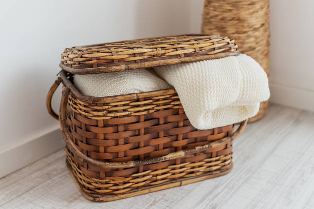 A wicker straw and bamboo chest of drawers, in the interior with bedspreads, blankets, a blanket and towels. For interior decoration. stock photo