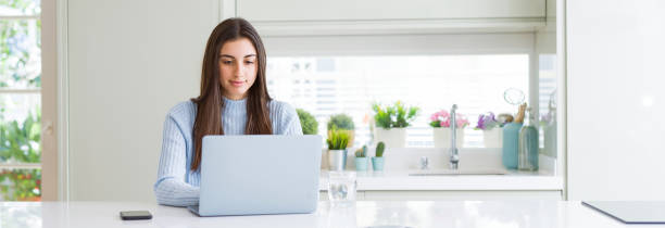 Wide angle picture of beautiful young woman working or studying using laptop with a confident expression on smart face thinking serious Wide angle picture of beautiful young woman working or studying using laptop with a confident expression on smart face thinking serious wide stock pictures, royalty-free photos & images
