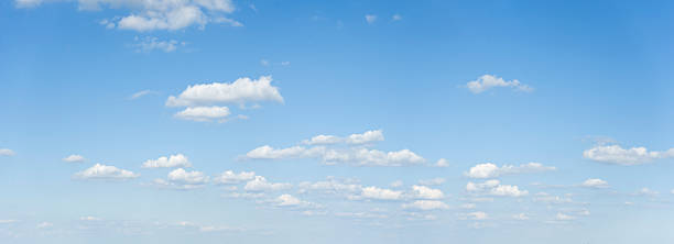 wide cloudscape on a clear blue sky - breed stockfoto's en -beelden