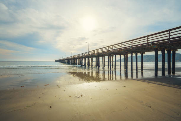 Wide long wooden pier on the beach with beautiful cloudy sky on background, California coastline stock photo